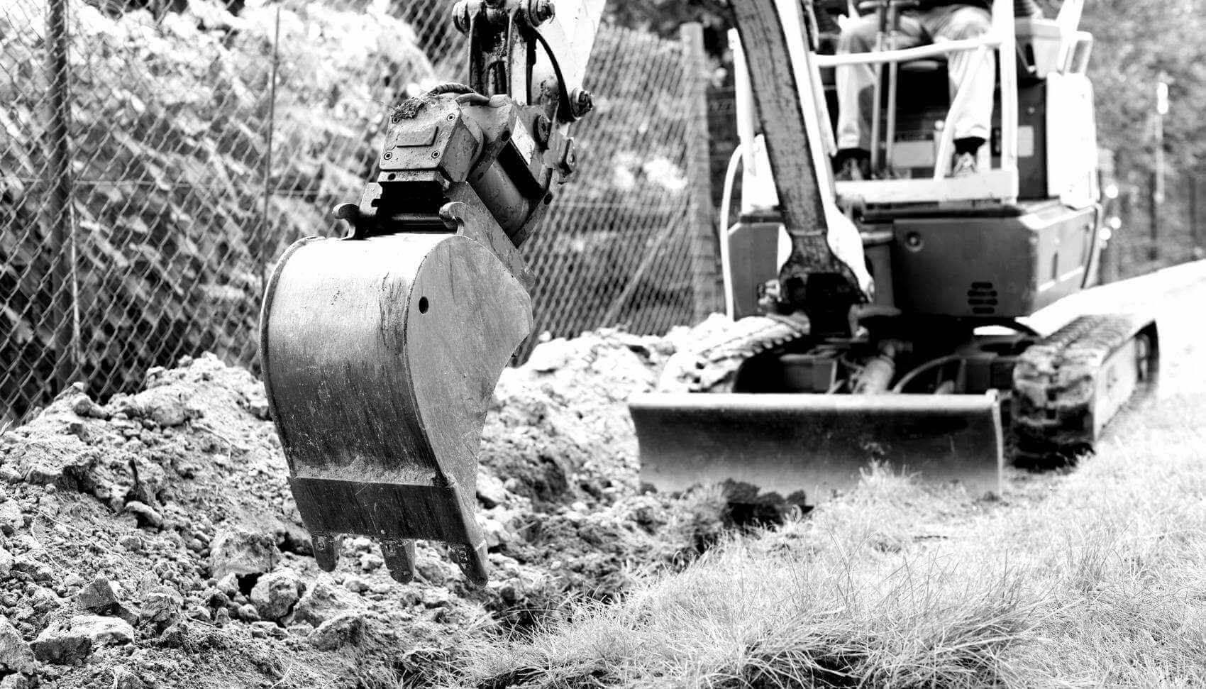 Small excavator digging in trench.