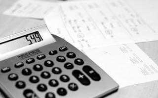 Photo of a calculator and bills on a desk.