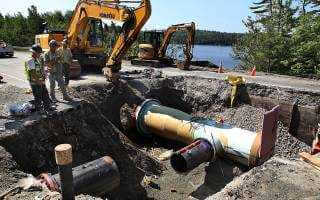 Workers and machinery installing underground conection pipe